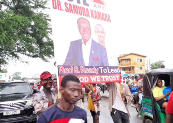 Supporters of the All People's Congress' Dr Samura Kamara carry his campaign poster outside the Atuga Mini Stadium in the east end of Freetown on Monday May 29, 2023. Photo credit, Kemo Cham, ManoReporters. The party has said it wouldn't participate in governance after disputing the June 24 polls.
