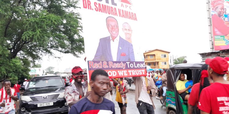 Supporters of the All People's Congress' Dr Samura Kamara carry his campaign poster outside the Atuga Mini Stadium in the east end of Freetown on Monday May 29, 2023. Photo credit, Kemo Cham, ManoReporters. The party has said it wouldn't participate in governance after disputing the June 24 polls.