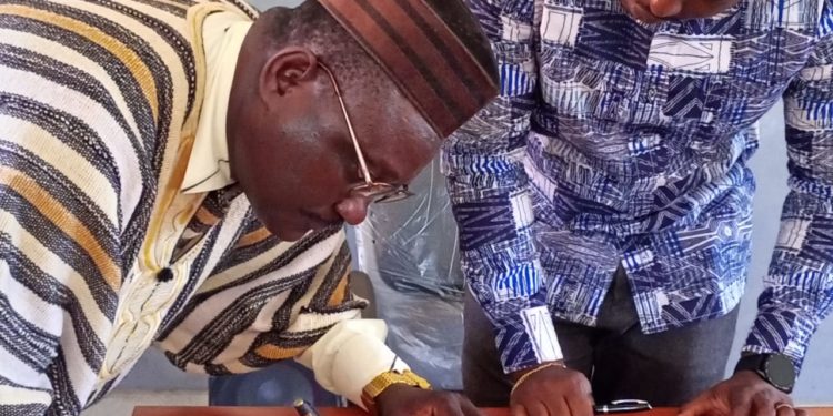 Chief Ismail Koroma, Chiefdom Speaker Small Bo Chiefdom, signing the by-law as District Medical Officer Dr Donald Grant looks on. Photo credit, James Flee, manoReporters