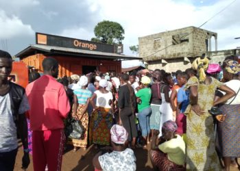 People queue up at an Orange Mobile Money outlet in Pujehun Town, waiting to be paid as part of the Emergency Cash Transfer programme by the government of Sierra Leone. Phot credit, Brima Sannoh, ManoReporters.