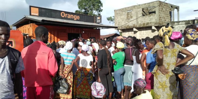 People queue up at an Orange Mobile Money outlet in Pujehun Town, waiting to be paid as part of the Emergency Cash Transfer programme by the government of Sierra Leone. Phot credit, Brima Sannoh, ManoReporters.